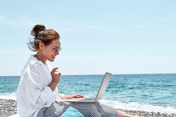 Pretty woman using laptop for online call at the beach. Businesswoman working outdoors. Technology and travel, freelance concept.Modern office.Distant work