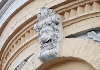 The facade of an old building decorated with a plaster lion
