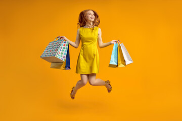 Full length photo of pretty redhead lady carry many shopping packs, addicted shopaholic in yellow...