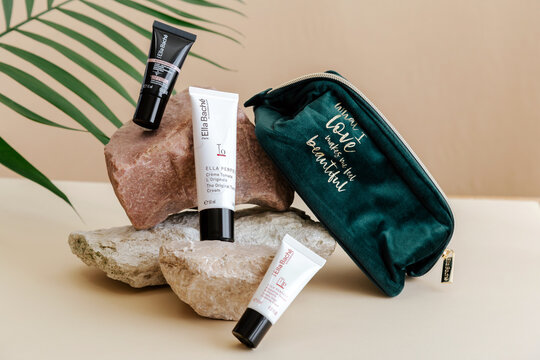 Ella Bache French Branded natural cosmetics for skin care. Set cosmetic products Ella Bache moisturizing cream serum cleanser in bag. Set brand beauty products on Stone pedestal with palm leaf