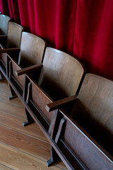 Vintage wooden theater and cinema chairs. Red curtain background
