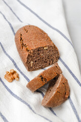 Delicious freshly baked bread with walnuts on white kitchen towel, vertical image.