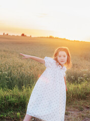 Fototapeta na wymiar beautiful little girl on background field at sunset