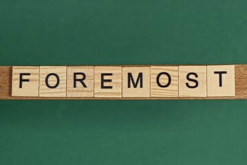 gray word foremost from small wooden letters on a green table