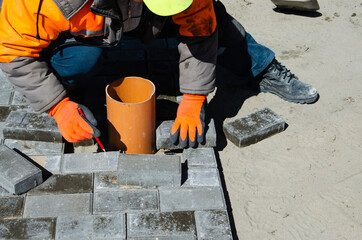 Construction of a sidewalk near the house. The bricklayer lays concrete paving stones for the device of a sidewalk path