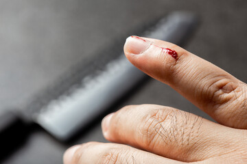 Bleeding finger by kitchen knife on black background
