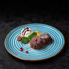 Chocolate fondant served on blue plate with ice cream and berries on dark table
