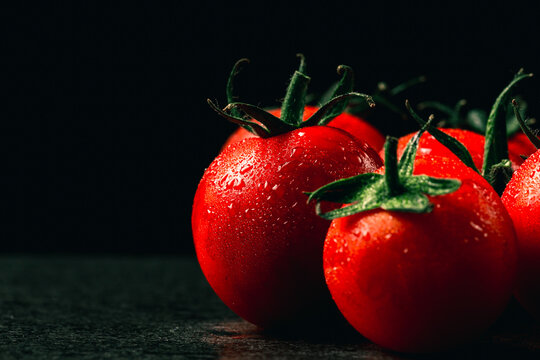 fresh tomatoes with wet and droplet on black stone table and black background, vintage flim picture style.