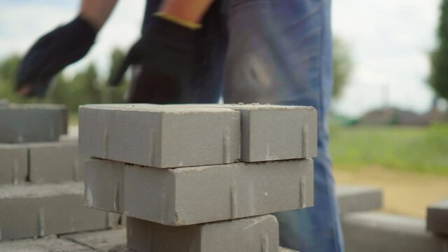 A worker lays a stack of bricks or paving slabs, for better transfer to the place of work or transportation.. He folds a stack on a sunny summer day.