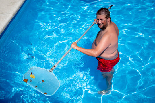 A man in the pool cleaning it
