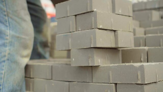 A worker lays a stack of bricks or paving slabs, for better transfer to the place of work or transportation.. He folds a stack on a sunny summer day.