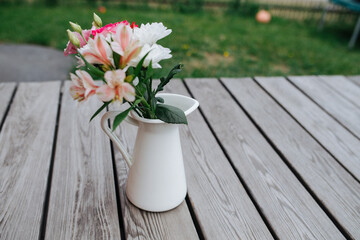 Bouquet of garden flowers in a vase on a rustic table at country cottage. Close up.