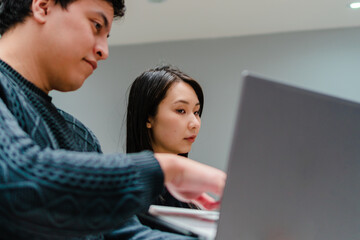 multiracial asian american woman, department head, checking computer exposed by latino employee