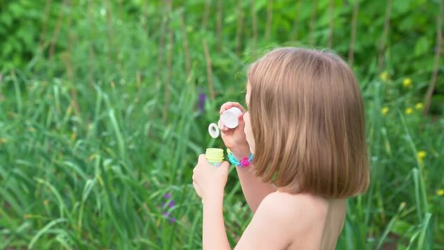 A girl inflates soap bubbles in a meadow. happy childhood and fun for children