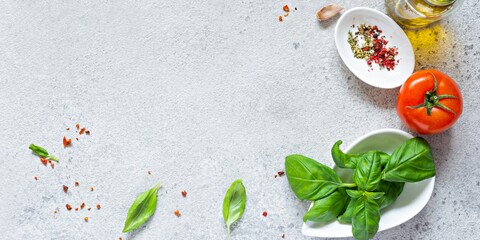 Fresh vegetables and herbs with spices on a gray background. Food background. Flatlay of ripe tomato, fresh basil leaves, garlic and spices, healthy food concept, copy space.