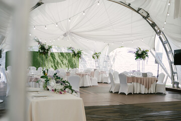 Wedding decoration of a photo zone and tables with fresh flowers, tent decor