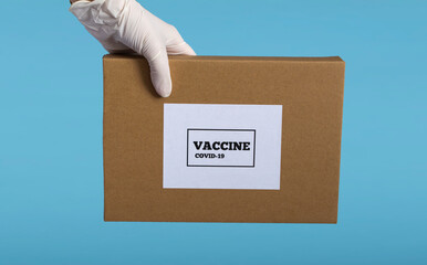 A medical professional in medical gloves holds a box of covid19 vaccine isolated on a blue background close-up