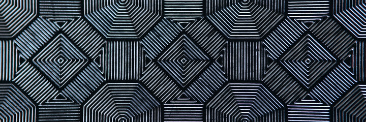 Black patterned tiles in form of rhombuses closeup