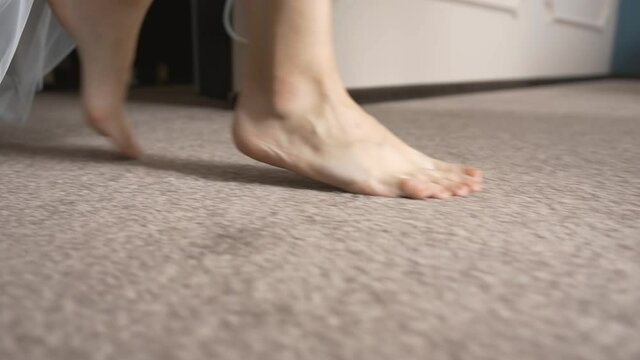 Caucasian girl steps with clean feet on the carpet. The morning of the bride with a long veil begins with a walk around the room. Easy happy gait of the fiancee