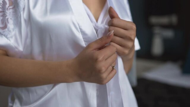 Morning of the bride. The girl is standing in a white nightgown and satin robe and holding hands on the collar of a bathrobe.
