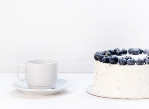 White curd torso with blueberry decoration.next to a white cup and saucer.space for text. High quality photo