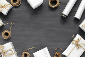 Rolls of wrapping paper, package gift boxes, present eco rope on black vintage table. Creative...