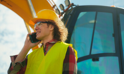 Excavator operator in hard hat talking by smartphone.