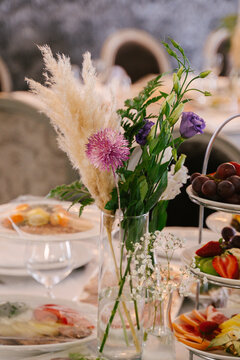 Flower arrangements in transparent small vases on guest tables, decor