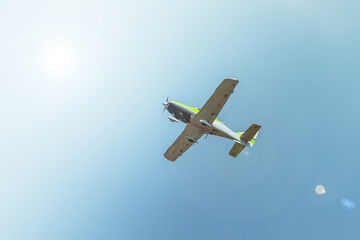 A white and green passenger plane is flying high in the sky on a bright sunny day.