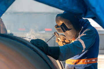 Welder is welding with shielded metal arc welding process with covered electrode to pipeline in the...