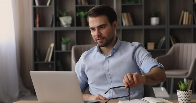 Millennial handsome man finished project on computer takes off glasses lean on comfortable ergonomic office chair relaxing put hands behind head. Stress relief after succeed result work done concept