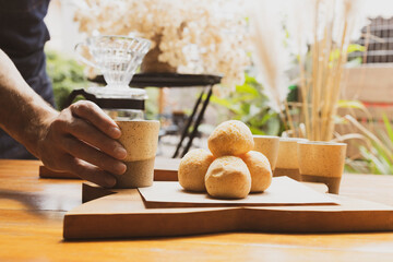 Brazilian organic artisanal bakery serving breakfast with a coffee mug and delicious cheese bread "pão de queijo". Natural decoration out of focus on the background. Small business concept.