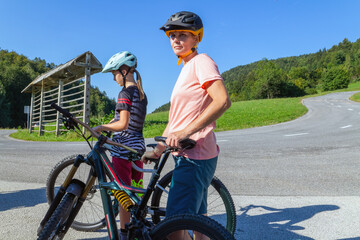 Obraz premium Mother and daughter cyclist resting on a country road.