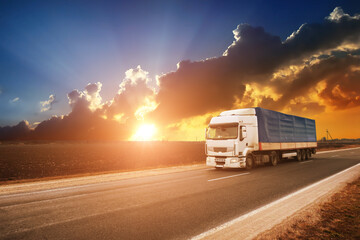 Plakat Big truck with a trailer on a countryside road with a sky with a sunset