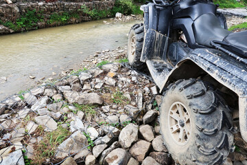 Close-up of a black ATV on a rocky coast of a mountain river