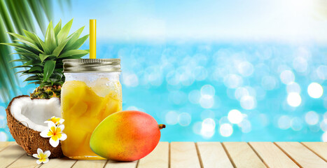 Summer tropical cocktail drink of mango fruit and coconut juice on blue turquoise sea background