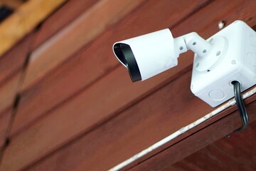 Concept : home security system. IP CCTV camera installed on wooden wall of house.