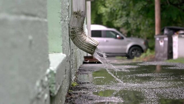 Close up from water coming from downspout in rainy day slow motion 