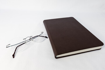 notebook and glasses on a white background. the concept of development through reading and learning.