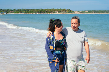 Latin couple walking on the beach in summer