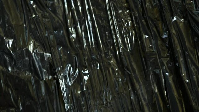 Black plastic wrap or polyethylene bag. Crumpled vinyl. Ecological problems. Recycling of recyclable materials. Packaging for goods. Dark stretch film. Polyvinylchloride. Background copy space texture