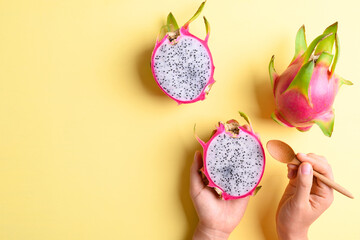 Dragon fruit or pitaya holding by woman hand with spoon for eating on yellow background, Tropical fruit