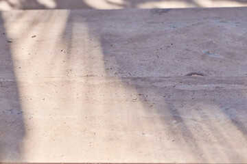 Premium texture with tropical palm leaf shadow on beige natural stone wall. Minimal trendy abstract concrete texture background for cosmetic product presentation. 