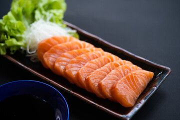 Salmon Sashimi in Japanese buffet restaurant menu.Fresh salmon fillet on black plate salmon slices.Asian people eating sashimi set Japan restaurant.salmon sashimi.Asian Food Menu.seafood sashimi.