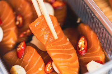 Fresh raw salmon slide marinated in a mild soy-sauce based brine on delivery go box.Asian people...