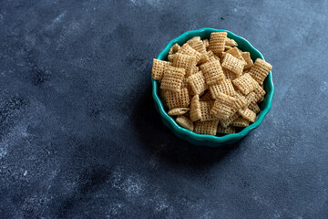 Chex cereal in a teal container on a dark background.