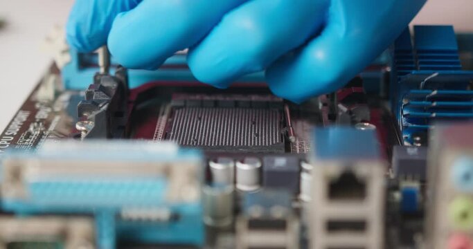 Close-up of repairing details for laptop computer, fixing mainboard micro chip in protective gloves. Electronics, disassembly of computer components processor at workplace in repair service center. 