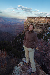 a woamn standing on a cliff over the valley of Grand Canyon during a sunset