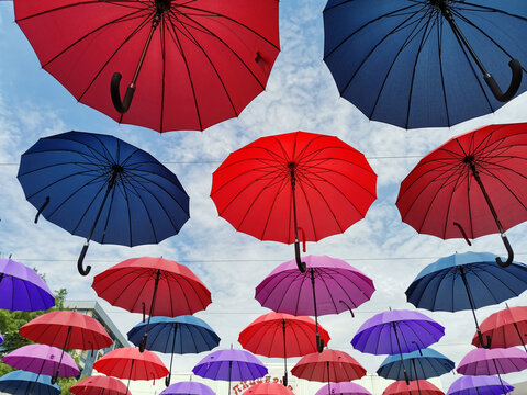 multicolored umbrellas hang against the blue sky