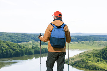 Man hiker observing the the green valley with lake and thinking. Travel Lifestyle wanderlust adventure concept summer vacations outdoor.